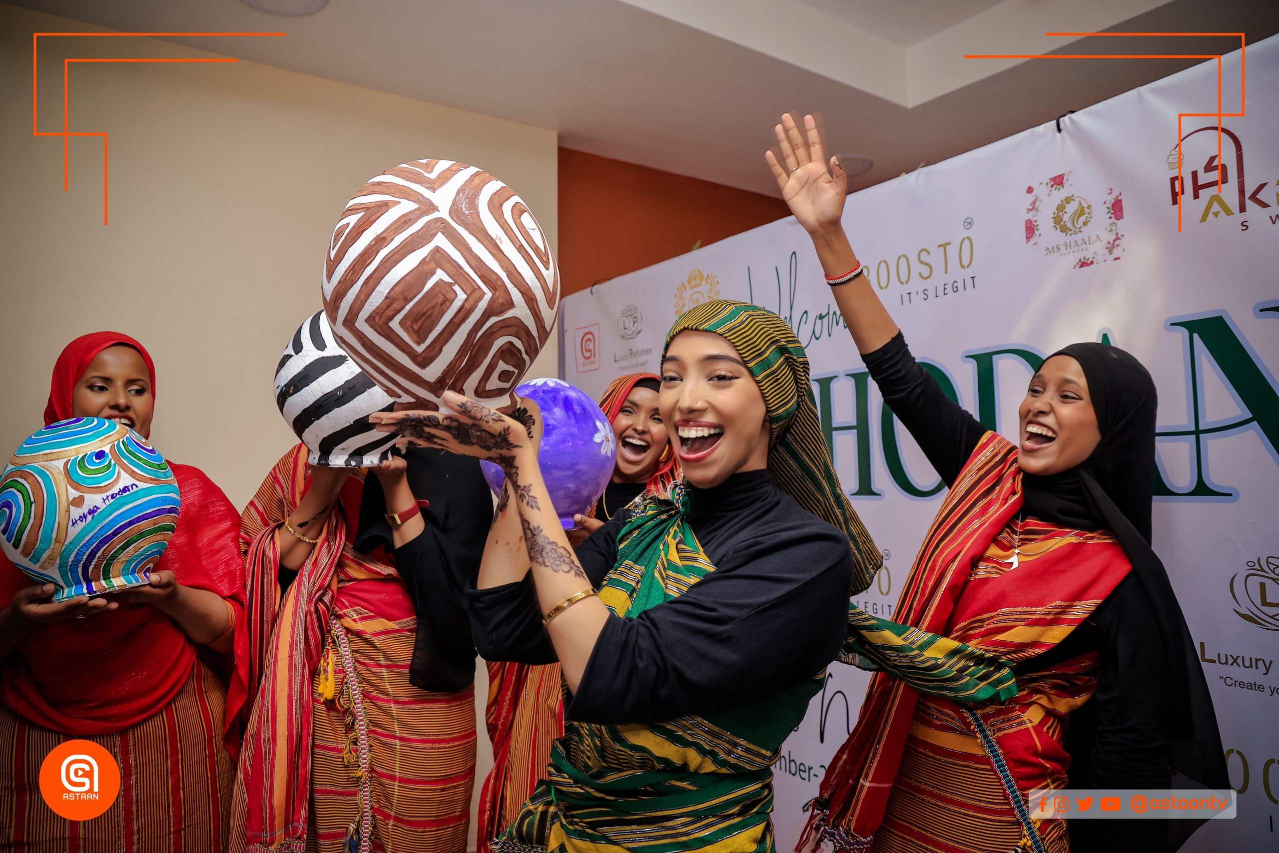 Young women in maroon striped garb sitting in a circle at an event