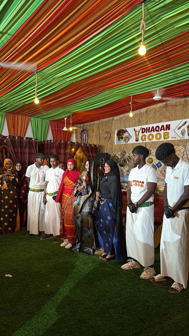 Two smiling women holding a golden gift bag at the sponsor backdrop